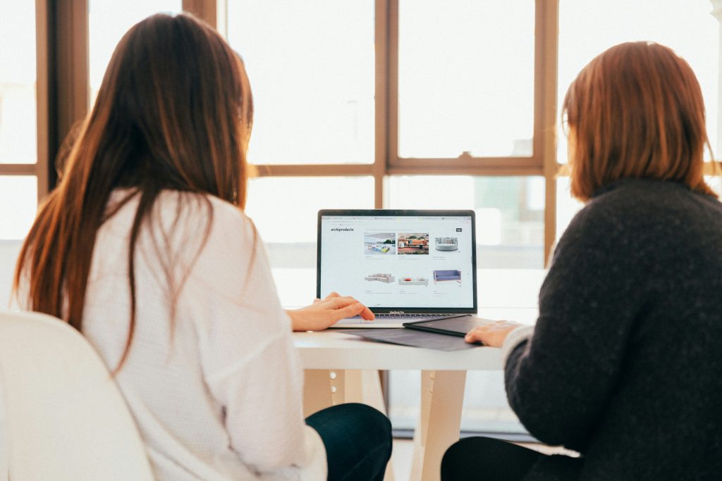 a group of women sitting at a table looking at a laptop